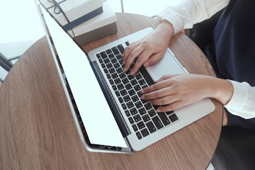 Close up of female's hands using laptop computer buying gifts, using laptop for online shopping. Online shopping concept.