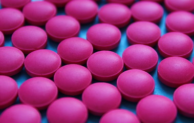 Texture of a lot of round pink pills scattered on the table