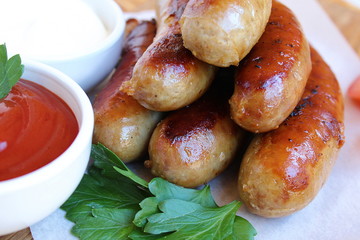 Pan-fried meat sausages with sauce and greens