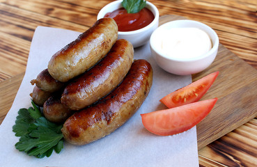 Pan-fried meat sausages with sauce and greens