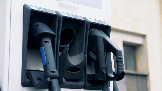 Male hand is pulling out an electric refueling nozzle to recharge an electrocar