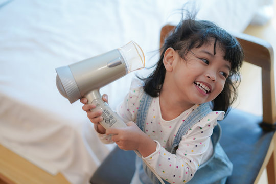 Asian little girl with curlers or hair dryer on her head and dries her hair after bathing.