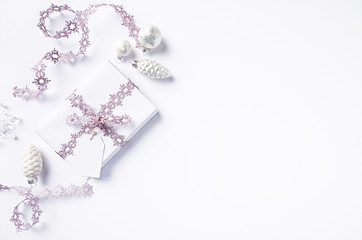 Christmas present wrapped in white paper and decorated with pink Christmas ribbon.  Flatlay. Copy space. White background