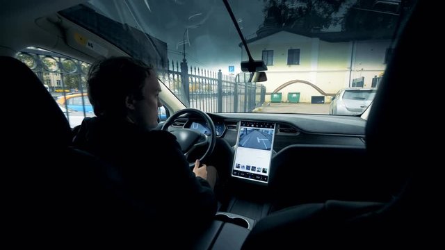 View from inside the car of a man driving off in it