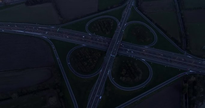 Night view of cloverleaf interchange seen from above. Aerial view of highway road junction in the night with evening traffic.