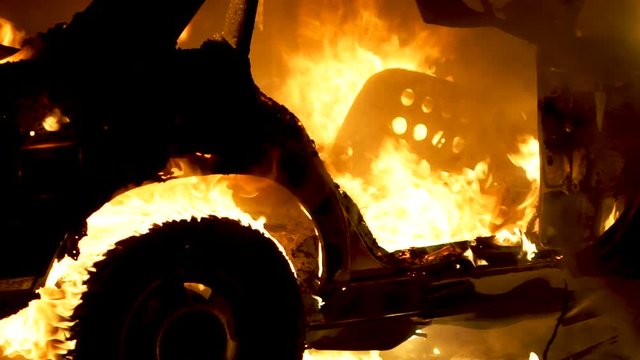 Burning car body, burning iron, broken car on fire in slow motion