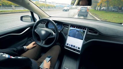 Inside view of an automobile which is driving by itself and a man sitting in it