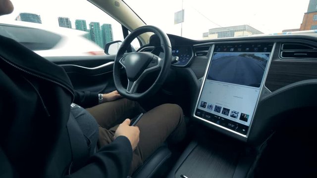 A man is sitting in a vehicle which is being automatically driven