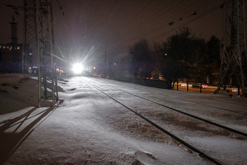 light from the train at night on the rails covered with snow in Russia