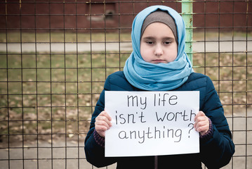 Refugee with text on paper standing outdoors