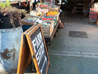 Farm Shop sign with produce outside, at Looe in Cornwall.