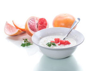 sweet oatmeal with slices of red grapefruit in a ceramic bowl