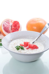 sweet oatmeal with slices of red grapefruit in a ceramic bowl