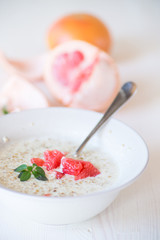 sweet oatmeal with slices of red grapefruit in a ceramic bowl