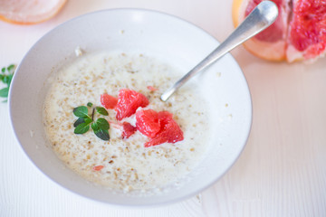 sweet oatmeal with slices of red grapefruit in a ceramic bowl