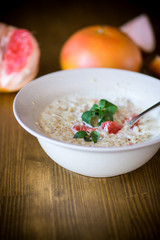 sweet oatmeal with slices of red grapefruit in a ceramic bowl