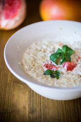 sweet oatmeal with slices of red grapefruit in a ceramic bowl