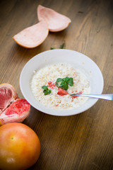 sweet oatmeal with slices of red grapefruit in a ceramic bowl