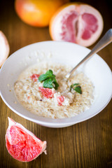 sweet oatmeal with slices of red grapefruit in a ceramic bowl