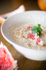 sweet oatmeal with slices of red grapefruit in a ceramic bowl