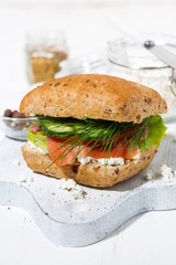 sandwich with salted fish, vegetebles and cream cheese on white wooden board, vertical closeup