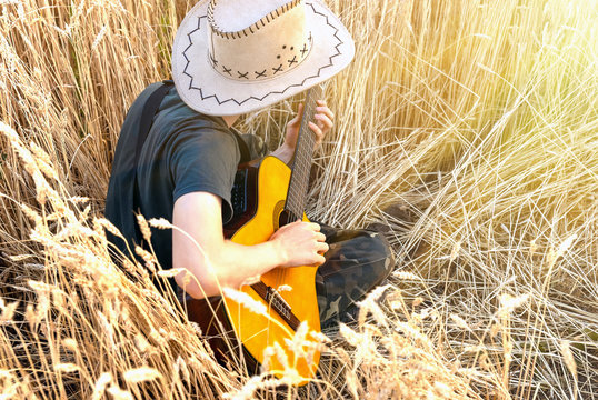 man in a cowboy hat plays an acoustic guitar