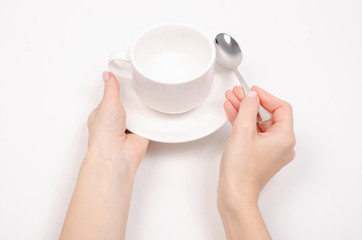 White saucer cup spoon in hand on white background isolation, top view