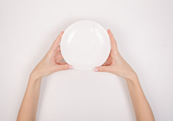 White saucer in hand on white background isolation, top view