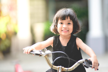 Fototapeta na wymiar Happy Asian kid girl of 3 or 4 years having fun when cycling on the bicycle . practice, sports, childhood concept