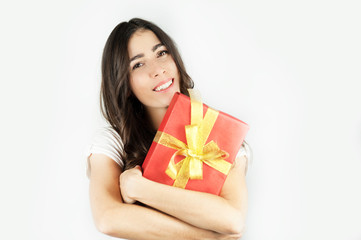 A young beautiful girl holds in her hands a big gift that keeps near the ear and listens to what is inside