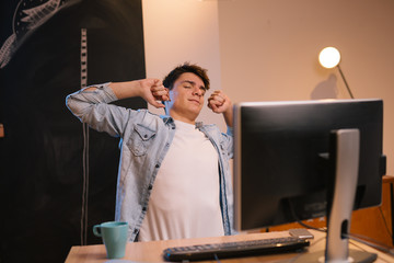 man tired from working on computer stretching his arms