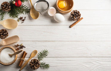 Christmas frame with eggs, sugar, species and fir cones on a white wooden background with copy space. Flat lay