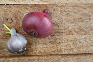 Garlic and red onion on the wooden board for vegetables