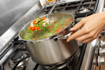 WOMAN IN KITCHEN COOKING MIXED VEGETABLES