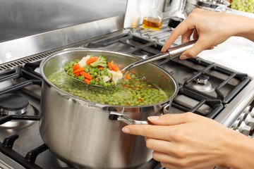 WOMAN IN KITCHEN COOKING MIXED VEGETABLES