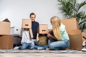 Picture of parents and children with cardboard boxes on their heads in new apartment