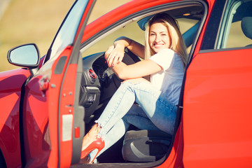 Photo of young blonde sitting red car