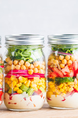Jars with layering vegan salad for healthy lunch with place for text. The concept of fitness and vegetarian food.
