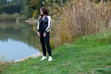 Brunette in tracksuit posing by the lake