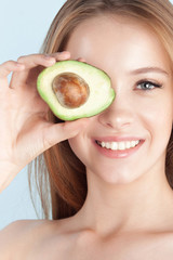 Young beautiful girl smiling with avocado close-up