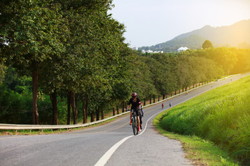 Fototapeta premium Sport and healthy woman riding the bike up the hill along road side of Banpra Reservoir located in Chonburi of Thailand