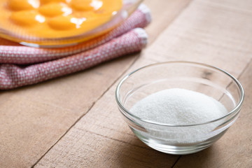 Dish of sugar with a bowl of egg yolks in the background