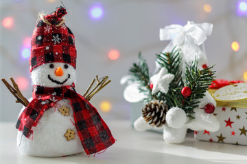 Snowman with christmas tree, gift boxes and christmas lights on the background