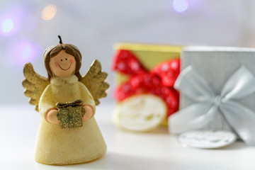 Christmas angel with gift boxes and christmas lights on the background