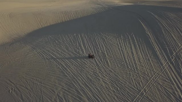 2K Aerial view of Dune buggie with a passenger and ATVs race across Mui Ne Sand Dunes in Vietnam at sunset. 