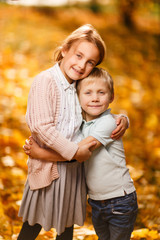 Photo of embracing brother and sister standing in autumn park