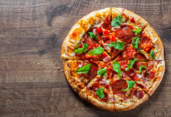 sliced Pepperoni Pizza with Mozzarella cheese, salami, chorizo, tomato sauce, pepper, Spices and Fresh arugula. Italian pizza on wooden table background