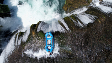 group of people doing white water rafting activity on wild river with waterfall