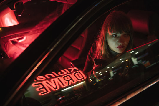 Young woman in car with smartphone and reflection of Kibiniai drive inscription