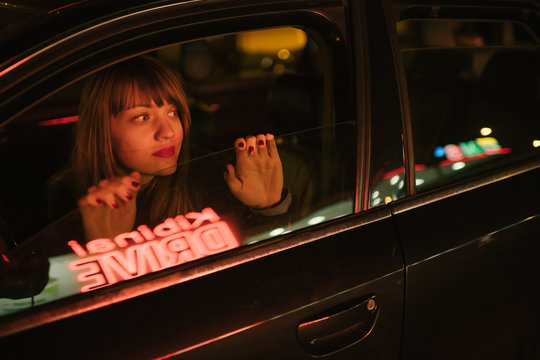 Young woman in car looking away and reflection of Kibiniai drive inscription